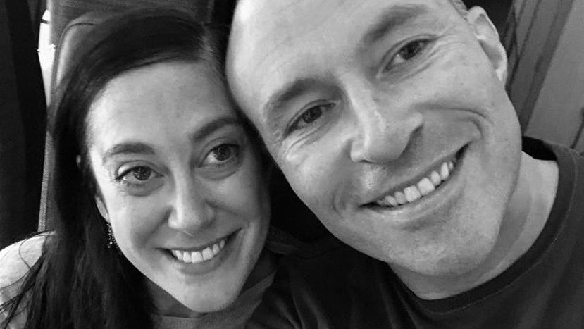 Black and white photo of Avila and Jason sitting close together, smiling.